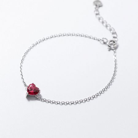 Detailed view of the silver heart bracelet featuring a vibrant red zircon stone.