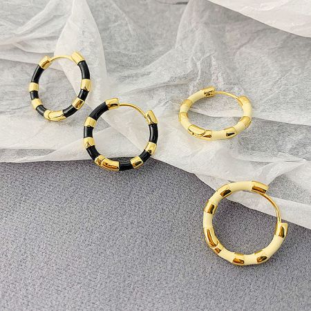 Collection of brass enamel hoop earrings in classic black and white with gold details, shown in pairs.
