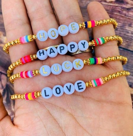 Beaded Letter Stretch Dainty Stackable Bracelet - A collection of four Beaded Letter Stretch Dainty Stackable Bracelets, spelling out the words hope, happy, luck, and love with colorful beads.