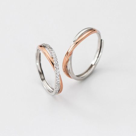 Two interlocking Möbius couple rings, one in polished silver and the other adorned with cubic zirconia.