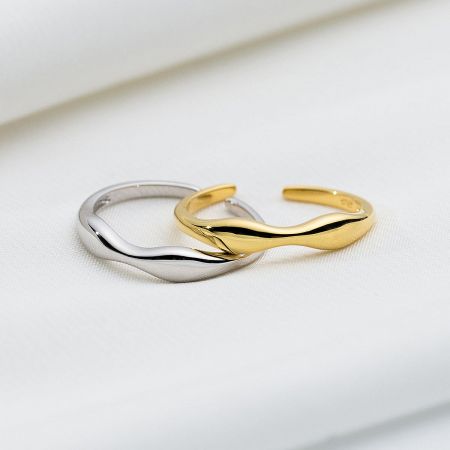 Close-up detail of the intertwined gold and silver wavy Mobius strip rings.