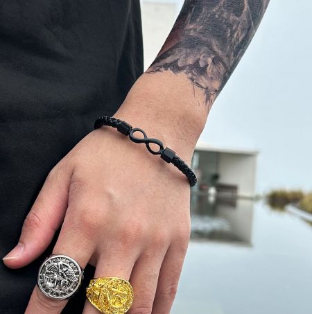 Infinity leather bracelet displayed with complementary silver and gold rings to showcase versatility.
