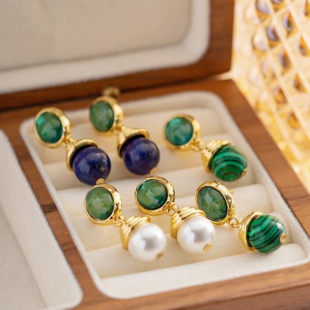 An assortment of natural stone earrings, including lapis lazuli and malachite, presented in a rustic wooden jewelry box.
