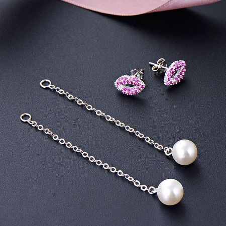 Detailed view of the pink gemstone stud and pearl tassel chain on the silver earrings.