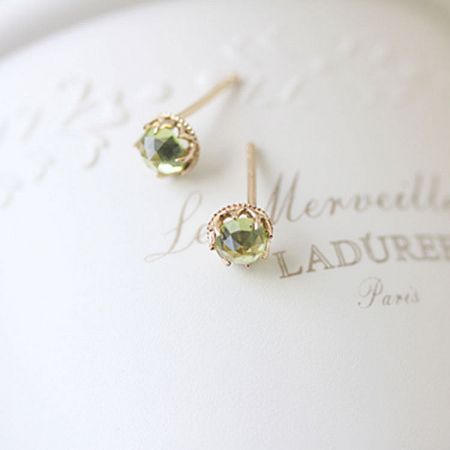 A pair of elegant peridot stud earrings showcased on a LADUREE Paris box.