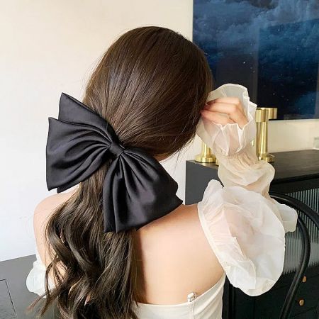 Wholesale Big Ribbon Bow Hair French Clips (Set of 5) - A woman with dark hair wearing a large black fabric ribbon bow French clip, showcasing its elegant style.