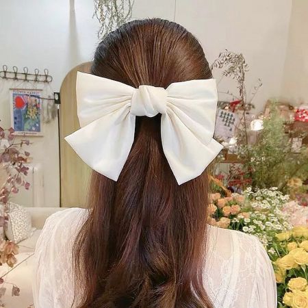 A model with long brown hair styled with a large white fabric bow.