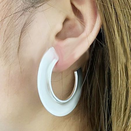 Side profile of a model wearing the large geometric C hoop earring in a silver finish.