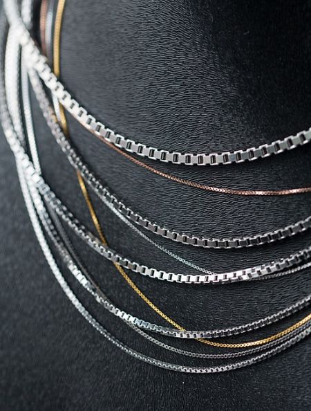 An elegant display of layered sterling silver necklaces, showcasing different colors and textures available for custom orders.