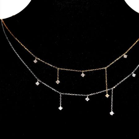 Layered sterling silver and gold zircon charm necklaces displayed on a mannequin.