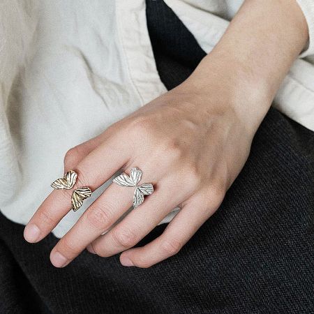 A hand modeling the leaf-design rings from the set in both gold and silver tones.