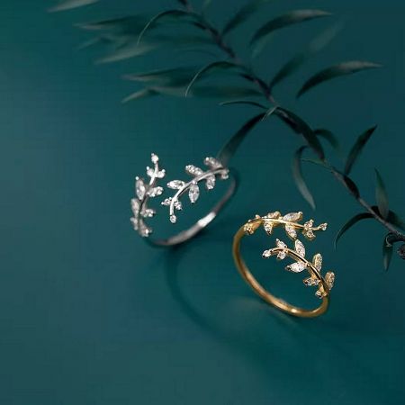 A pair of leaf design rings in both silver and gold finishes displayed together.