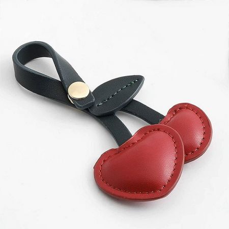 A versatile red cherry charm displayed on a black leather strap.