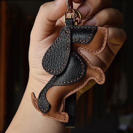 Close-up of the Basset Hound leather keychain in black and brown with a gold metal ring.