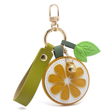 Close-up of a lemon slice PU leather keychain with a green wristlet strap and gold bell charm.