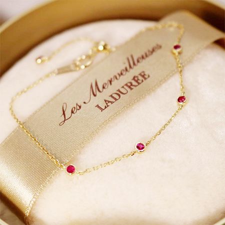 Product shot of the gold-plated bracelet with red gemstones, emphasizing its luxurious appeal.