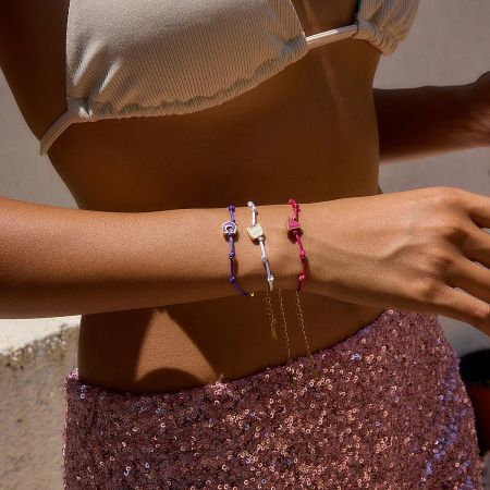 Lifestyle shot of a woman wearing multiple gold-plated initial bracelets, showcasing their stylish and stackable design.