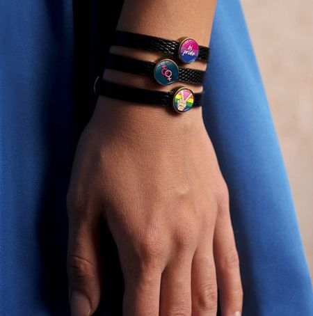 Various styles of LGBTQ+ pride bracelets displayed together, showcasing the rainbow enamel details.