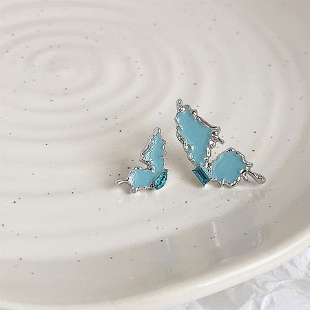 Full set of five pairs of asymmetrical butterfly stud earrings displayed on a decorative plate.