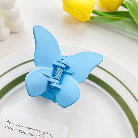 Close-up of the light blue butterfly hair clip showing its matte texture.
