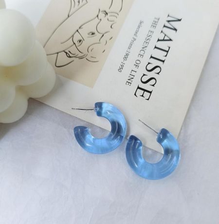 Close-up of light blue resin acrylic hoop earrings.