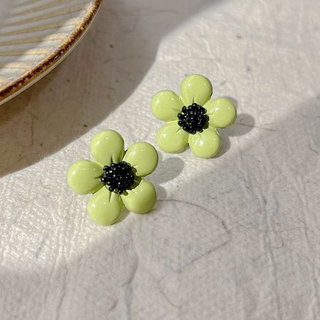 Detailed shot of the light green enamel daisy earrings with black centers.