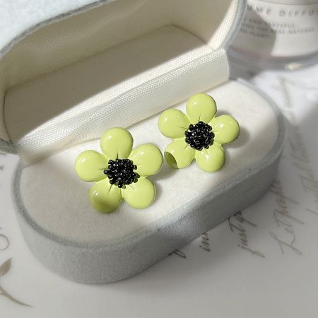 Top-down view of the green daisy flower earrings presented inside a heart-shaped box.