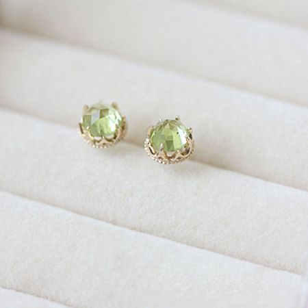 Detailed view of the light green peridot gemstones in their gold settings.