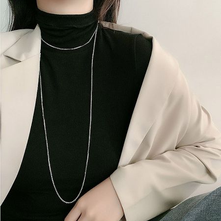 A detailed product shot of the long silver chain necklace, highlighting its texture and silver plating.