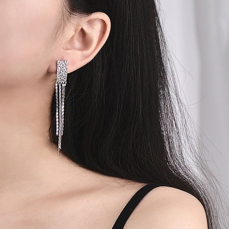 Side profile of a model wearing the long silver drop earring, emphasizing its elegant drape.
