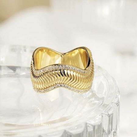 A luxury gold ring from the set, featuring a high-end design with a wavy pattern and zircon.