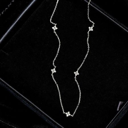 A luxurious silver necklace with a unique wavy chain and diamond-like motifs, displayed in a jewelry box.