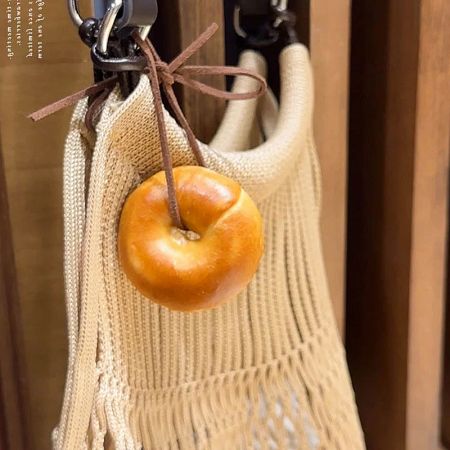The versatile bagel-shaped PU charm attached to a woven macrame bag.
