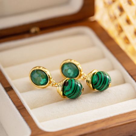 Close-up of a pair of drop earrings featuring striking green malachite stones set in polished gold-plated stainless steel.