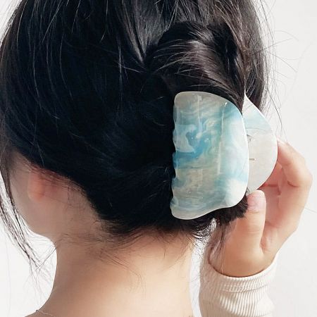 A blue and white marbled hair clip securing a woman's hair bun.
