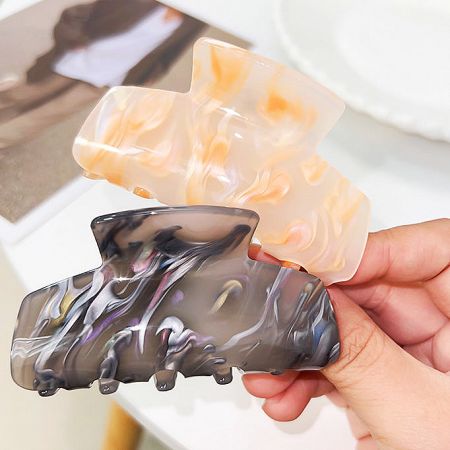 Two acetate hair clips in black and beige marbled designs.