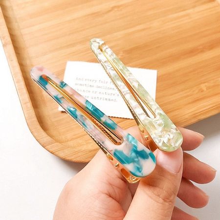 Close-up of two marbled hair clips with elegant gold accents.