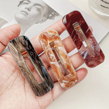 Three marbled hair clips in red, brown, and grey, showcasing the available color options.