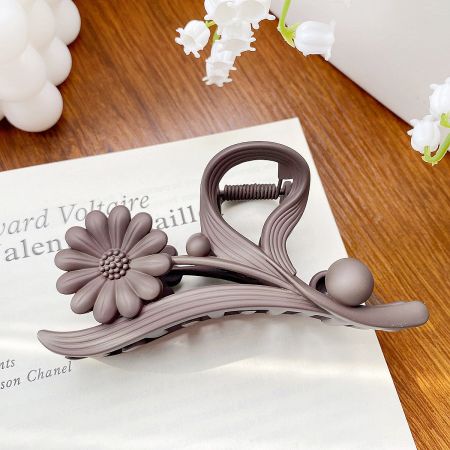 A mauve-colored daisy flower hair claw clip, highlighting its matte finish.