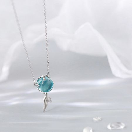 Close-up of the sterling silver fish-tail pendant with a luminous blue moonstone.