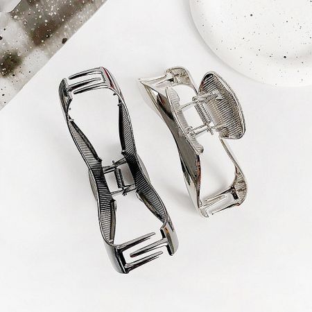 Two curve-shaped metal hair clips showcasing their strong spring mechanism and polished finish.