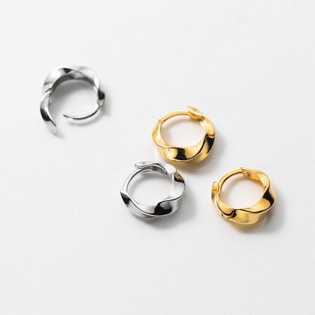 Both silver and gold versions of the Mobius twist hoop earrings displayed together.