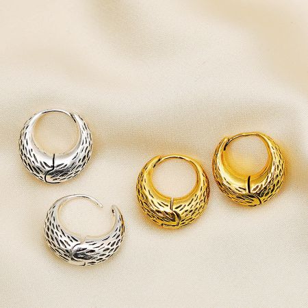 Detailed view of the textured, feather-like pattern on the silver and gold basket bag hoop earrings.