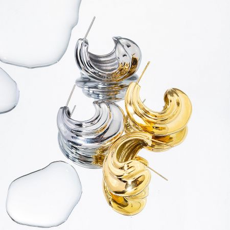 Three pairs of chunky geometric hoop earrings in gold and silver, showing their metallic sheen and twisted design.