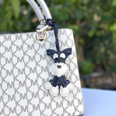 The Schnauzer dog charm attached to a stylish Michael Kors handbag, demonstrating its use as a bag accessory.