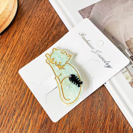 The mint green cat-shaped hair clip with glitter texture and pearl details.