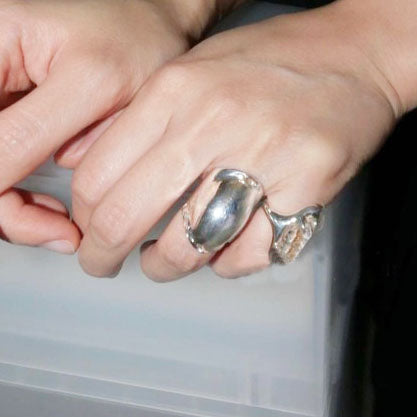 Modern styling of the silver brass rings on a model's hand.