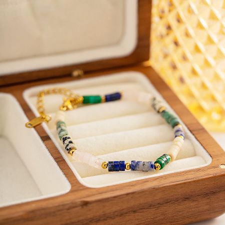 A detailed view of a multicolored bead bracelet with gold accents, nestled in a wooden box.