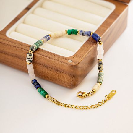 The boho bracelet with its gold clasp shown against a white surface and wooden box.