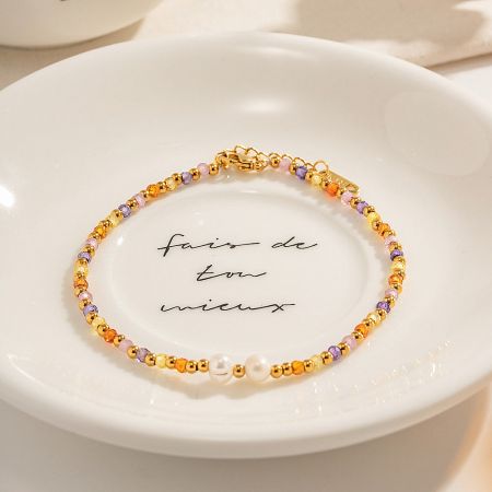 Showcase of a multicolored beaded anklet with pearls, displayed on a decorative plate.